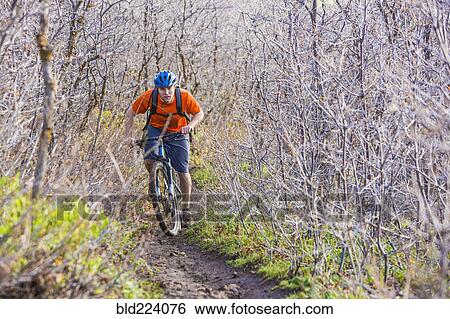 Stock Photograph - Caucasian man riding mountain bike in forest. Fotosearch