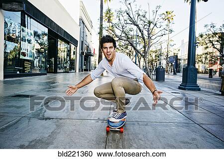 Stock Image - Caucasian man riding skateboard. Fotosearch