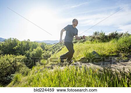 Stock Photo - Caucasian man running up staircase on hill. Fotosearch