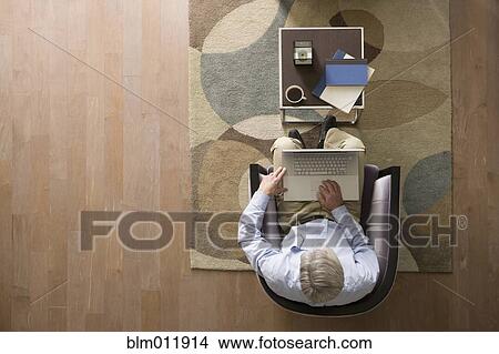 Caucasian man using laptop in living room View Large Photo Image Picture - Caucasian man using laptop in living room. Fotosearch