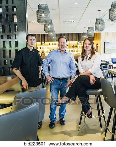 Stock Image - Caucasian men and woman smiling in restaurant. Fotosearch