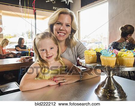 Stock Image - Caucasian mother and daughter smiling in cafe. Fotosearch