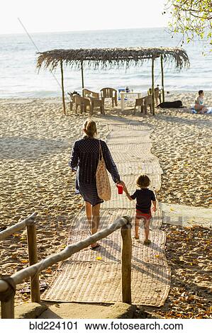 Stock Image - Caucasian mother and son walking on path to beach. Fotosearch
