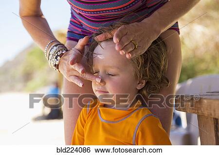 Stock Photograph - Caucasian mother applying sunscreen to face of son. Fotosearch