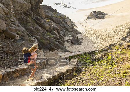 Caucasian sister carrying brother descending staircase to beach View Large Photo Image Stock Photo - Caucasian sister carrying brother descending staircase to beach. Fotosearch