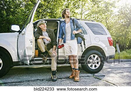 Stock Image - Caucasian sitting and standing at car. Fotosearch