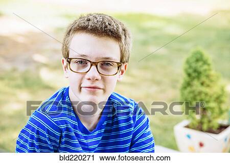 Stock Image - Caucasian teenage boy smiling in backyard. Fotosearch