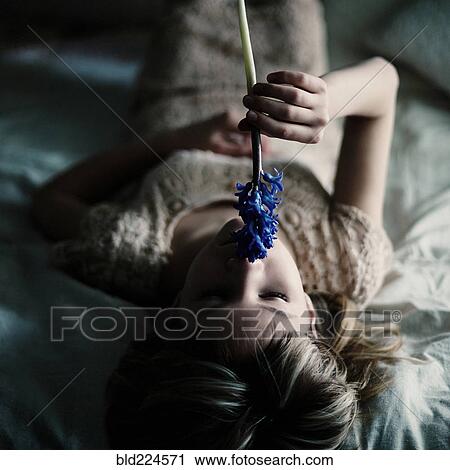 Stock Image - Caucasian teenage girl smelling flower. Fotosearch