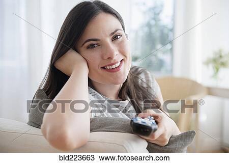 Stock Image - Caucasian woman aiming remote control. Fotosearch