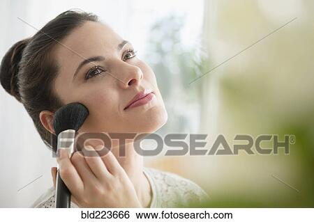 Stock Photograph - Caucasian woman applying blush. Fotosearch