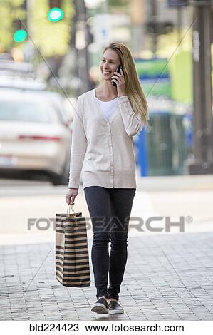 Caucasian woman carrying shopping bag using cell phone View Large Photo Image Stock Image - Caucasian woman carrying shopping bag using cell phone. Fotosearch