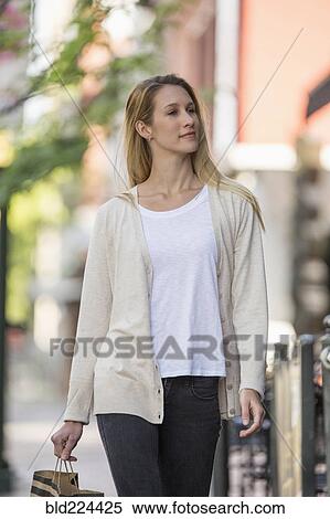 Stock Photography - Caucasian woman carrying shopping bag in city. Fotosearch