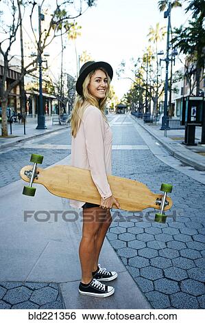 Stock Photograph - Caucasian woman carrying skateboard. Fotosearch