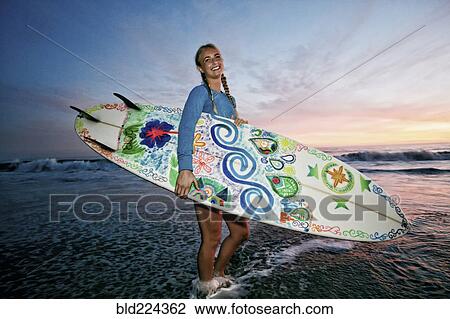 Caucasian woman carrying surfboard at beach View Large Photo Image Stock Image - Caucasian woman carrying surfboard at beach. Fotosearch