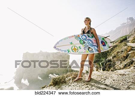 Caucasian woman carrying surfboard at beach View Large Photo Image Stock Photo - Caucasian woman carrying surfboard at beach. Fotosearch