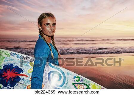 Stock Photo - Caucasian woman carrying surfboard at beach. Fotosearch