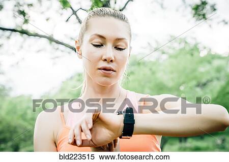 Stock Photography - Caucasian woman checking the time on wristwatch outdoors. Fotosearch