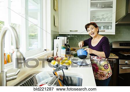 Stock Photo - Caucasian woman cooking in kitchen. Fotosearch