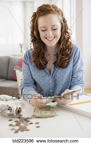 Caucasian woman counting money from savings jar View Large Photo Image Stock Photograph - Caucasian woman counting money from savings jar. Fotosearch