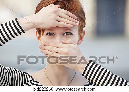 Stock Image - Caucasian woman covering mouth and forehead with hands. Fotosearch