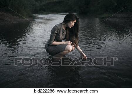 Stock Photograph - Caucasian woman crouching in remote stream. Fotosearch
