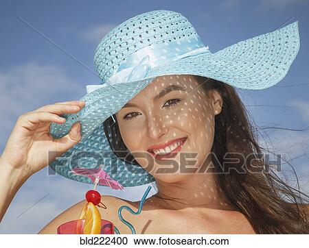 Stock Image - Caucasian woman drinking cocktail at beach. Fotosearch