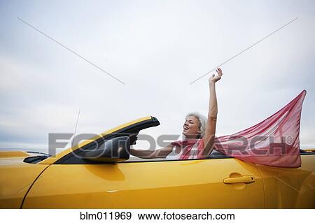 Stock Photo - Caucasian woman driving yellow convertible. Fotosearch