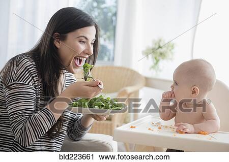 Caucasian woman eating salad while watching baby daughter View Large Photo Image Stock Image - Caucasian woman eating salad while watching baby daughter. Fotosearch