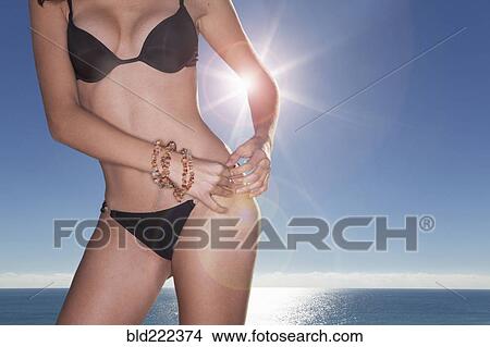 Caucasian woman fastening bikini bottom View Large Photo Image Picture - Caucasian woman fastening bikini bottom. Fotosearch