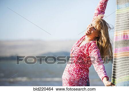 Picture - Caucasian woman holding blanket in wind. Fotosearch