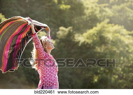 Stock Image - Caucasian woman holding blanket in wind. Fotosearch
