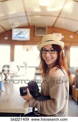 Stock Photo - Caucasian woman holding camera in restaurant. Fotosearch
