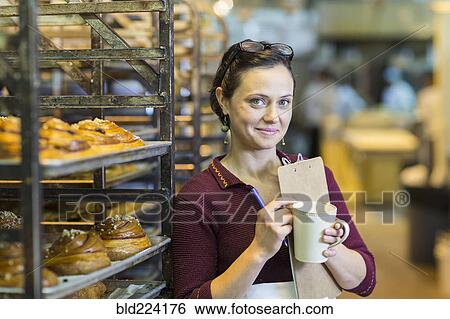 Caucasian woman holding clipboard drinking coffee in bakery View Large Photo Image Stock Photograph - Caucasian woman holding clipboard drinking coffee in bakery. Fotosearch