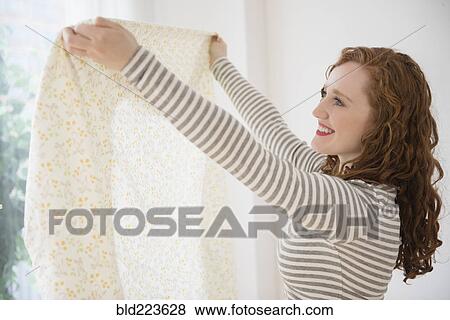 Stock Photo - Caucasian woman holding curtain at window. Fotosearch
