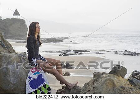 Caucasian woman holding skimboard on rock at beach View Large Photo Image Stock Image - Caucasian woman holding skimboard on rock at beach. Fotosearch