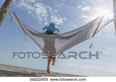 Stock Image - Caucasian woman in hammock at beach. Fotosearch