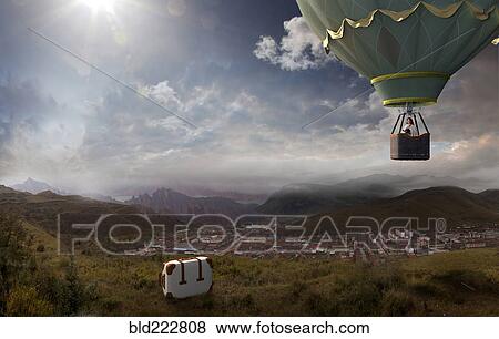 Stock Photo - Caucasian woman in hot air balloon forgetting suitcase. Fotosearch