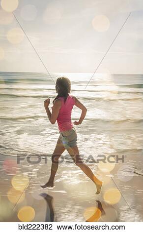 Stock Image - Caucasian woman jogging on beach. Fotosearch