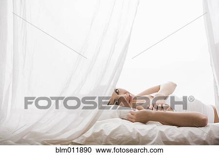 Stock Image - Caucasian woman laying in bed. Fotosearch
