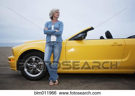 Stock Photograph - Caucasian woman leaning on convertible. Fotosearch