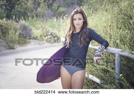 Caucasian woman leaning on railing holding skimboard View Large Photo Image Picture - Caucasian woman leaning on railing holding skimboard. Fotosearch