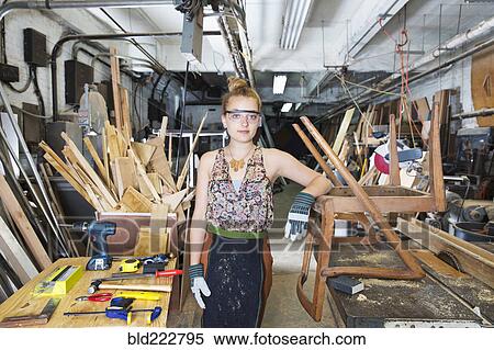 Stock Photography - Caucasian woman leaning on wooden chair in workshop. Fotosearch