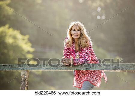 Stock Photograph - Caucasian woman leaning on wooden banister. Fotosearch