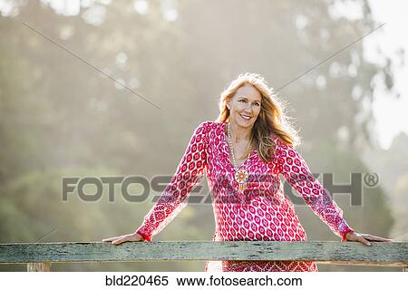 Stock Photography - Caucasian woman leaning on wooden banister. Fotosearch