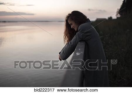 Stock Photo - Caucasian woman leaning over river wall. Fotosearch