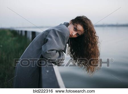 Stock Photograph - Caucasian woman leaning over river wall. Fotosearch
