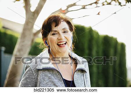 Stock Photography - Caucasian woman listening to earbuds outdoors. Fotosearch