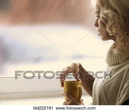 Stock Image - Caucasian woman looking out window. Fotosearch