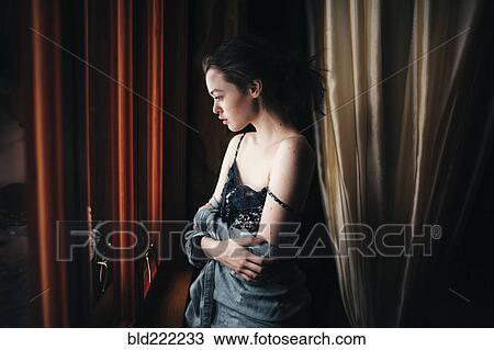 Stock Image - Caucasian woman looking out window. Fotosearch