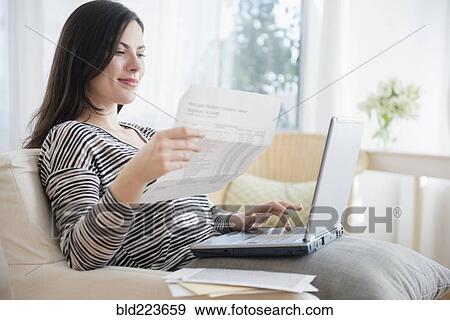Stock Photo - Caucasian woman paying bills using laptop. Fotosearch